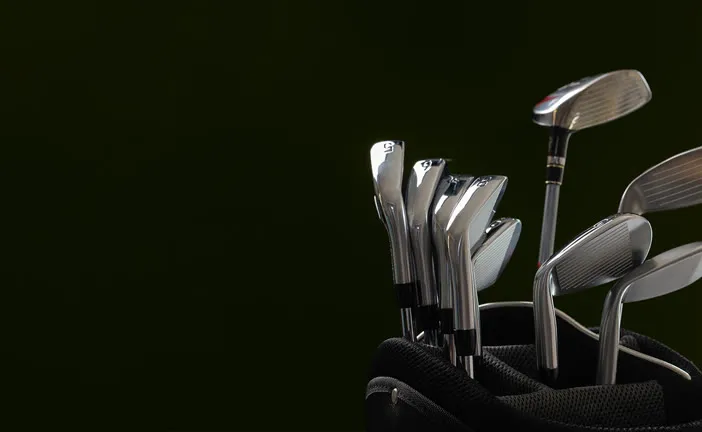 Set of golf irons against a dark background