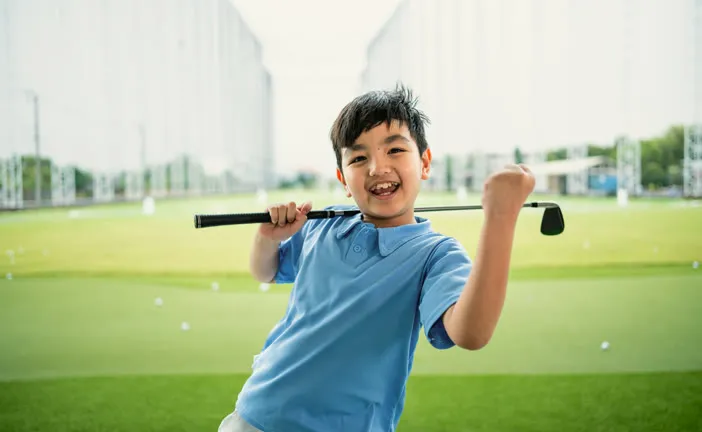 Boy cheering with his club at the driving range