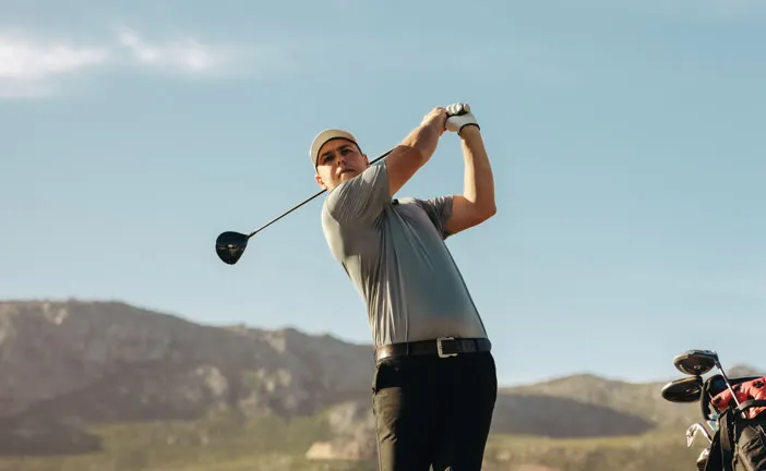 Golfer following through on a mountain course