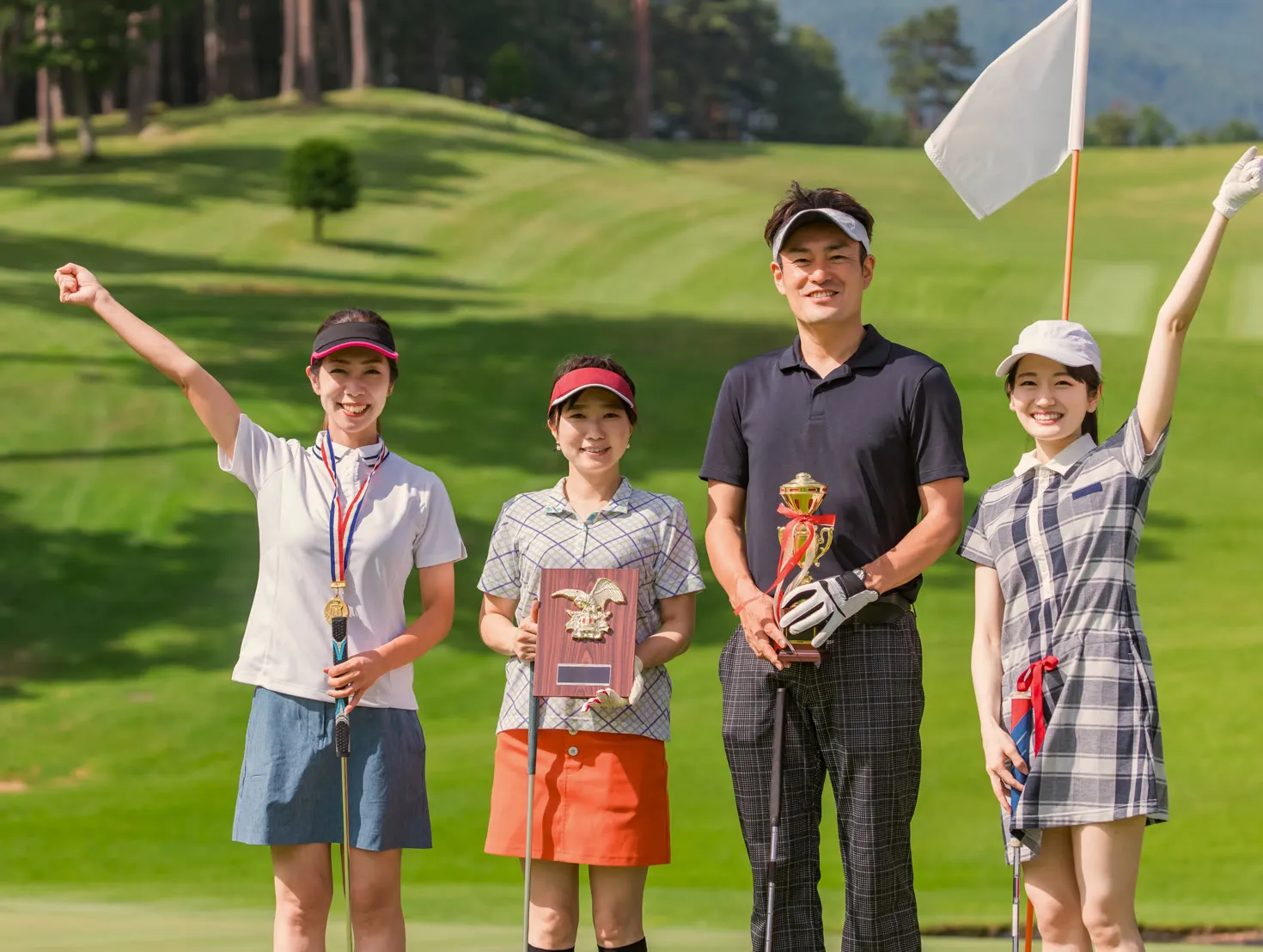 Smiling winners holding their trophies on the course