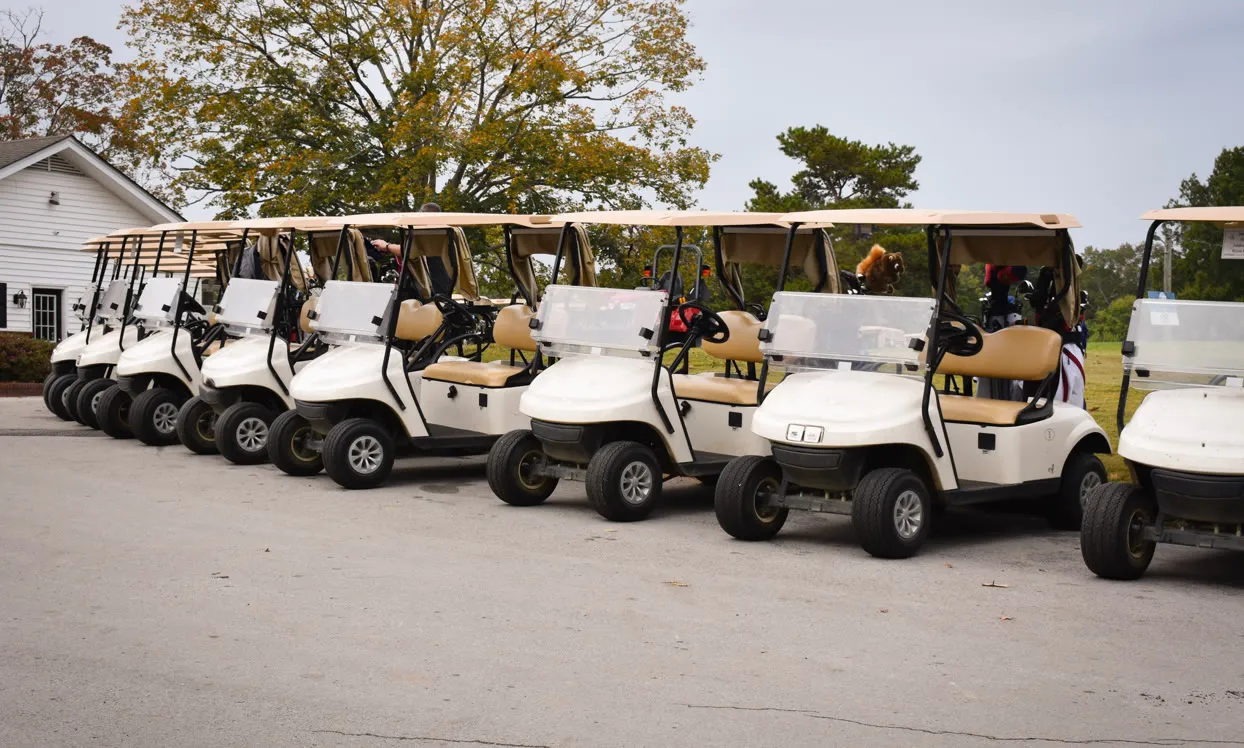 Row of white golf buggies outside the clubhouse