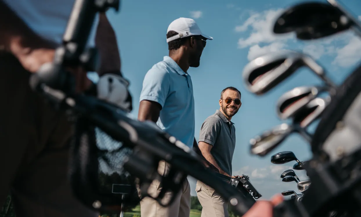 Golfers laughing beside their bags on a sunny day