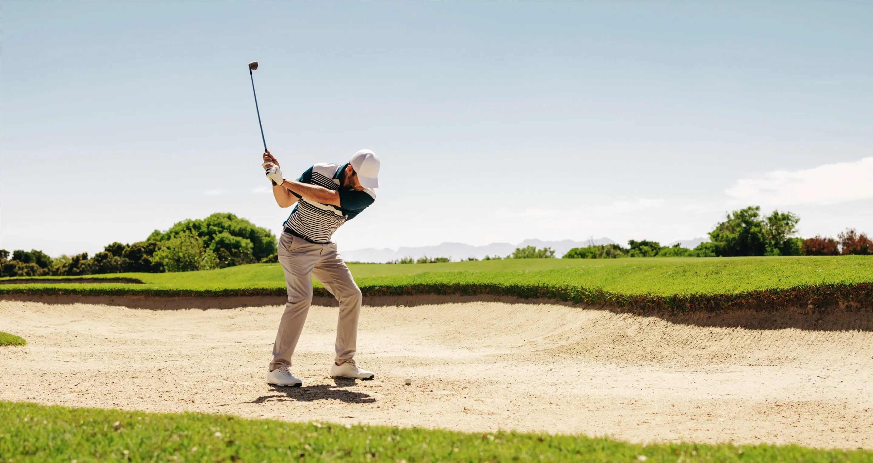 Golfer mid-swing on a sunlit fairway