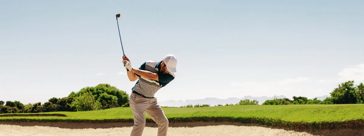 Golfer mid-swing on a sunlit fairway