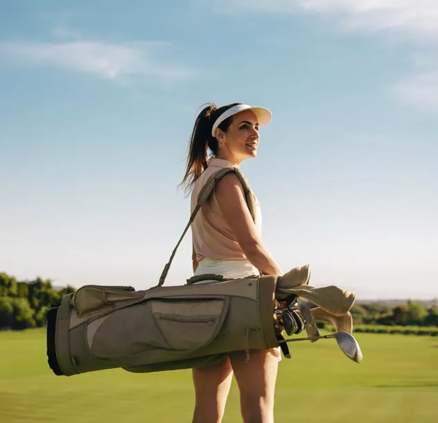 Golfer carrying her bag across the fairway