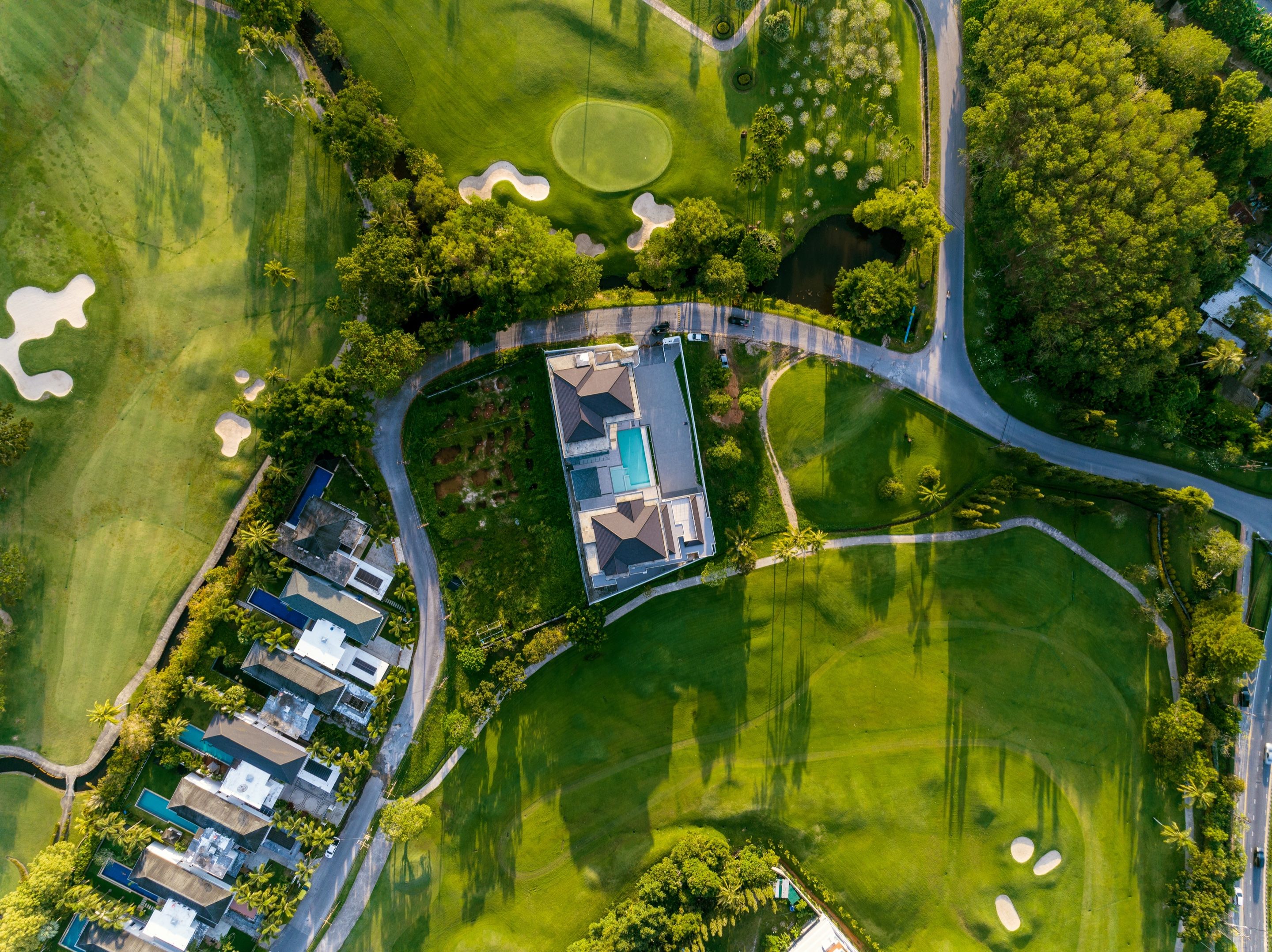 Aerial view of a villa between golf fairways and tropical trees