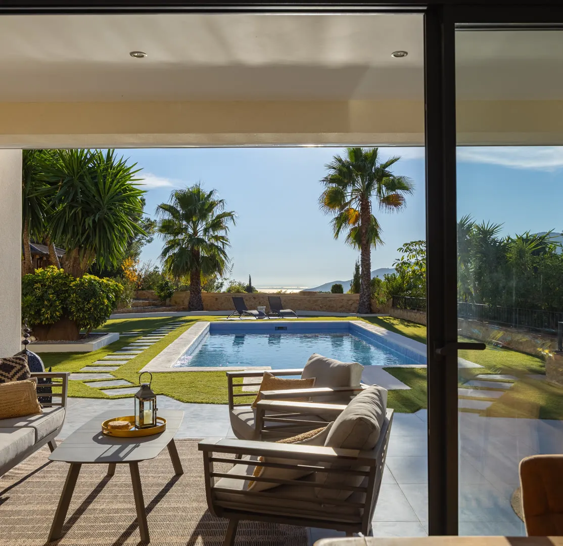 Shaded terrace lounge beside a pool and palms